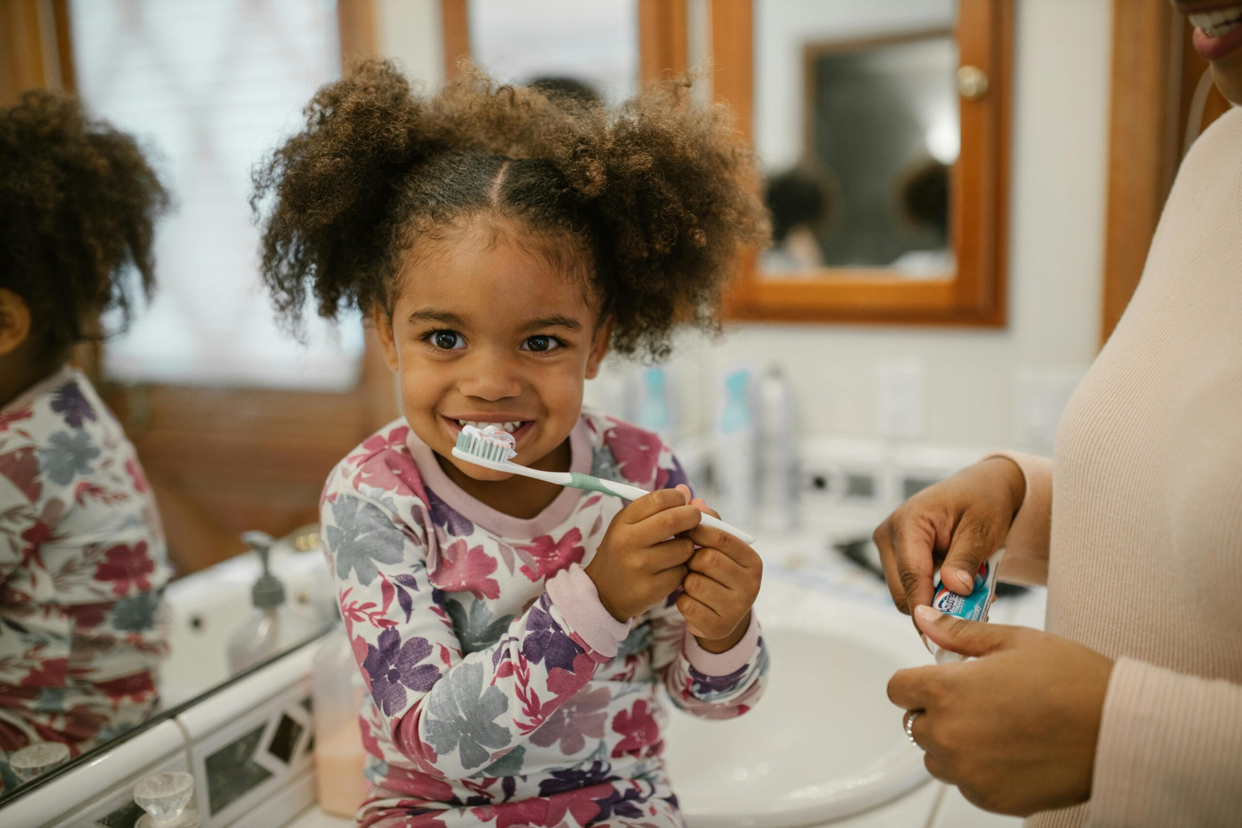 curly haired little girl brushing her teeth